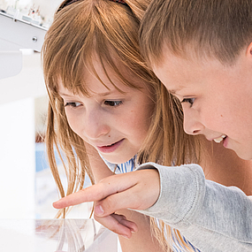 Kinder schauen in eine Vitrine